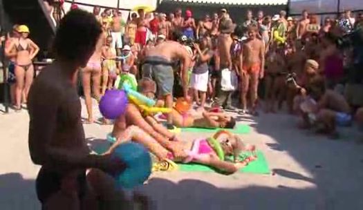 Полуголые девушки и парни весело проводят время на пляже под музыку